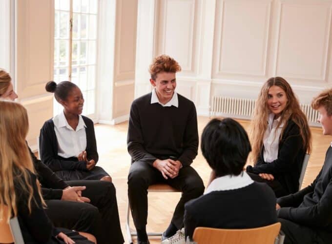Young people in school uniform in circle talking