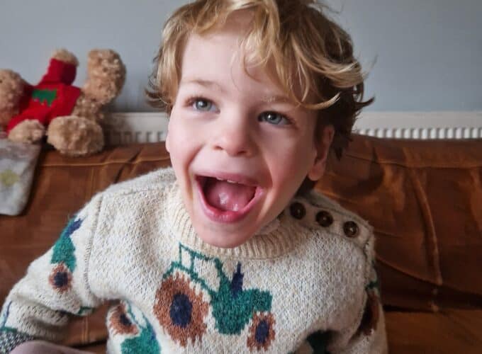 Little boy Ivan sitting on a sofa with a big smile on his face