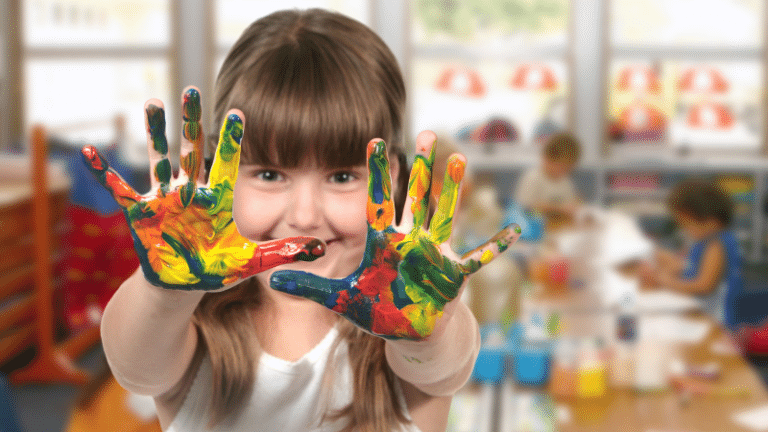 Girl holding up hands covered in paint