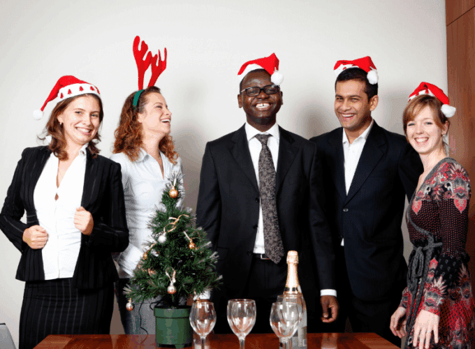 People wearing Santa hats, laughing with drinks on table