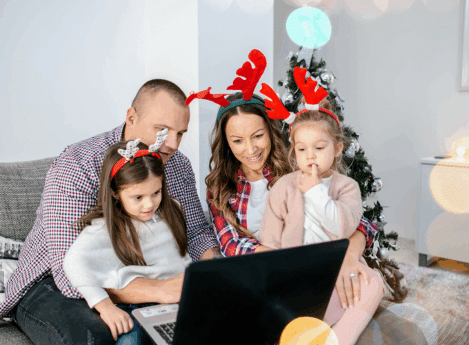 Family looking at a laptop wearing reindeer antlers.