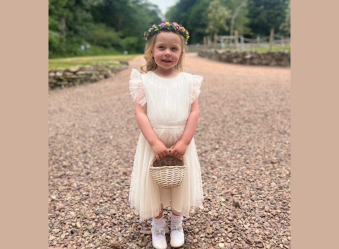 Neveah smiling in white dress with flower basket in hand
