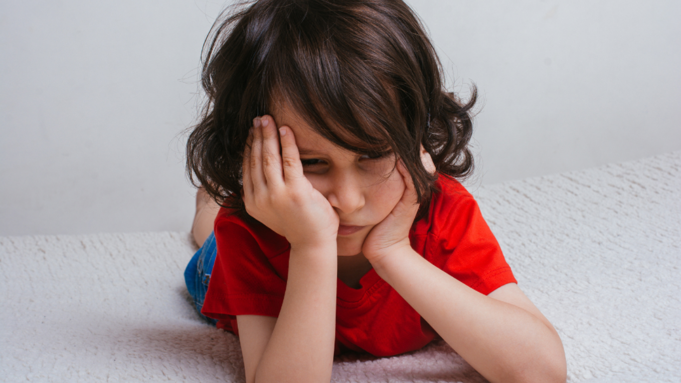 A child with his head in his hands looking sad.